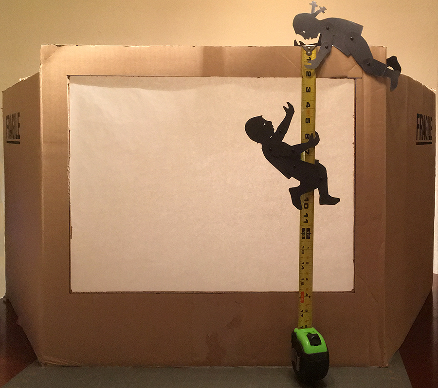 boy and girl shadow puppet climbing a measuring tape to make a cardboard box theater