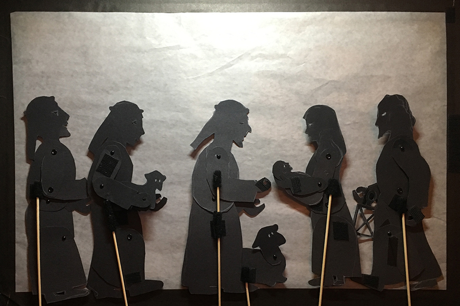 Shadow puppets of three shepherds admiring the baby in Mary's arms while Joseph standing by