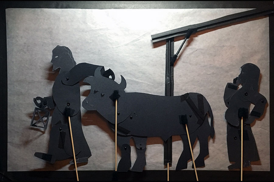 Shadow puppets of Joseph taking the oxen out off the manger while Mary watches 