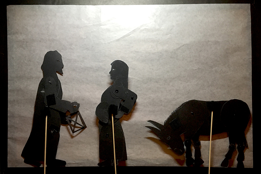 Shadow puppets of Joseph, Mary, and the donkey, with Mary stretching her back