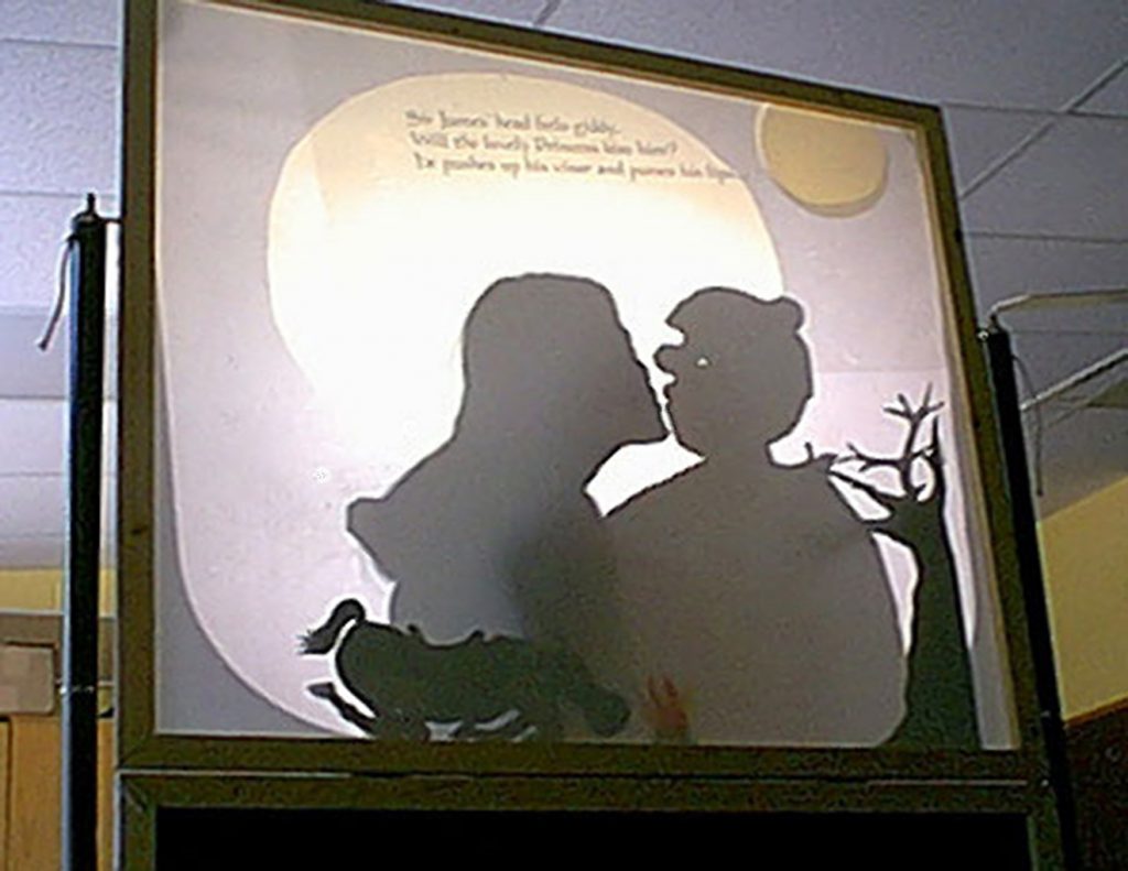 Shadow screen showing a teacher kissing a puppet knight projected from overhead projector