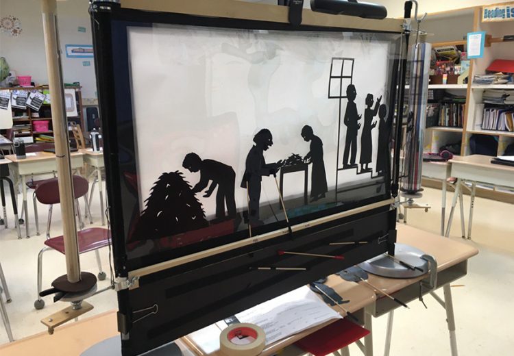 Back of a shadow puppetry screen with scrolling transparent film depicting the opening scenes of the story of Henry "Box" Brown