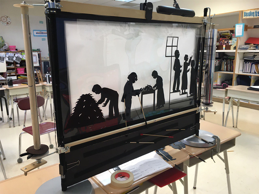 Back of a shadow puppetry screen with scrolling transparent film depicting the opening scenes of the story of Henry "Box" Brown