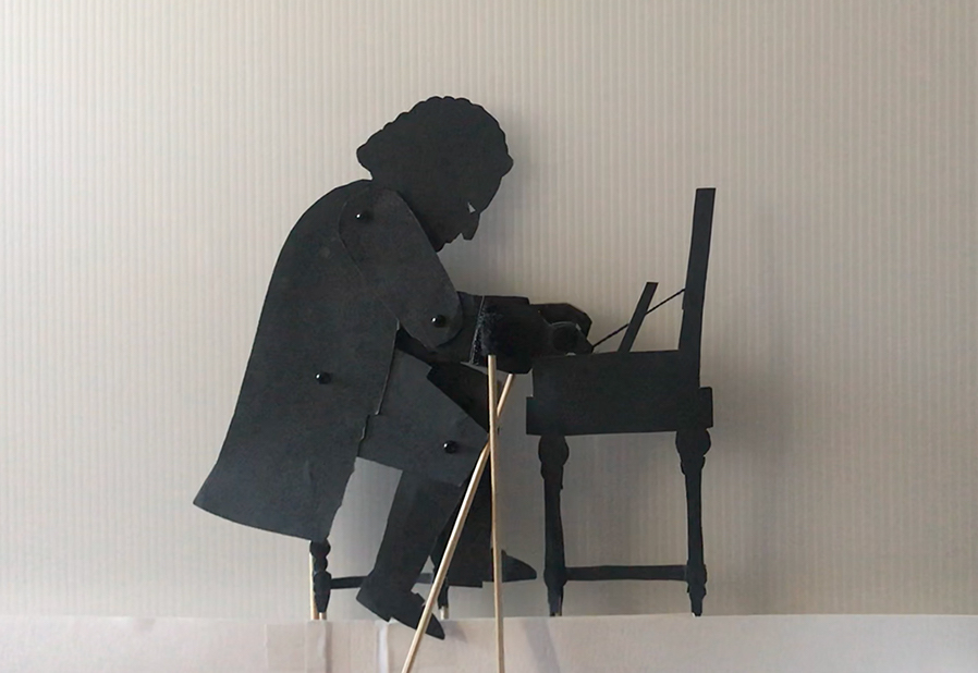 Shadow puppet of Bach playing the clavichord showing moving rods