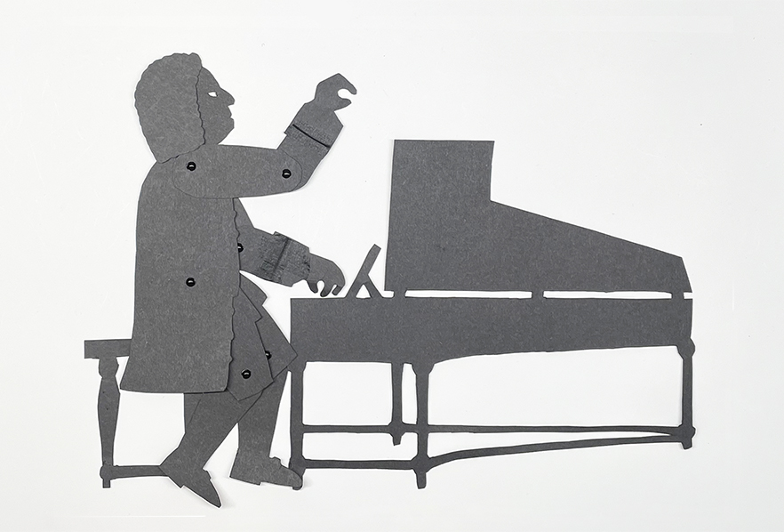 Puppet of Bach behind a harpsichord raising one hand