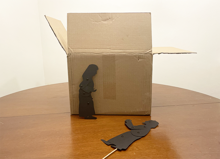 Box on a table with puppet of Mary standing against it