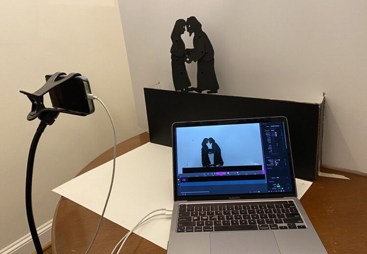 silhouette puppets of Joseph and Mary on a stand with a phone and laptop.