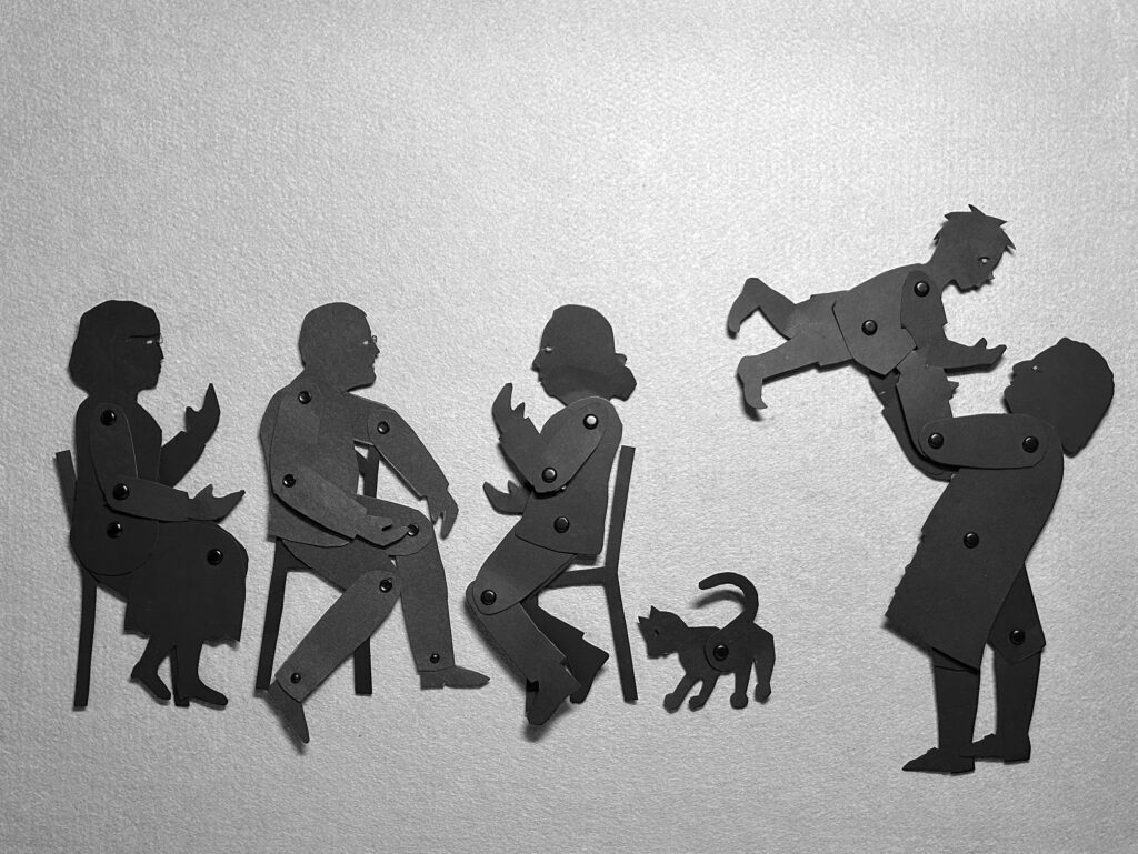 silhouette puppets of family gathering with three people talking, a cat, and a man holding up a child