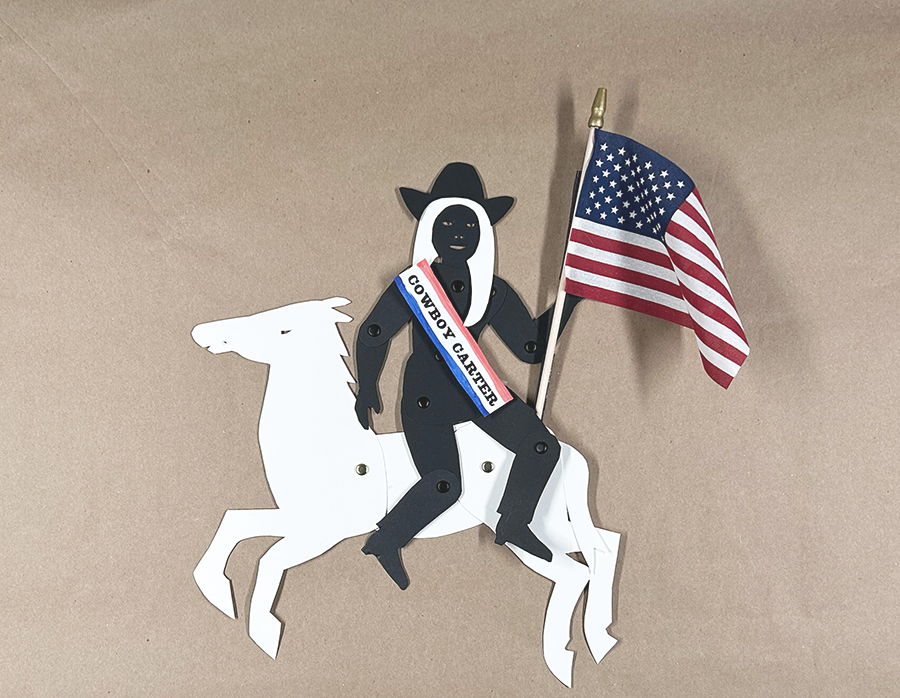 Black silhouette puppet of Beyonce with white hair, flag, and sahs sitting on a white paper horse