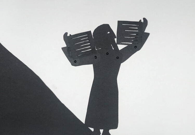 shadow puppet of bearded old man holding two annotated tablets above his head